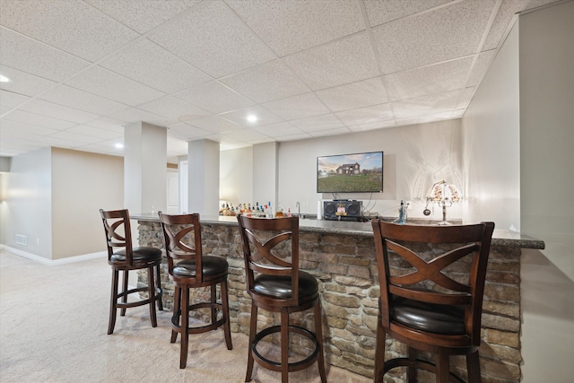 bar with a drop ceiling and light colored carpet