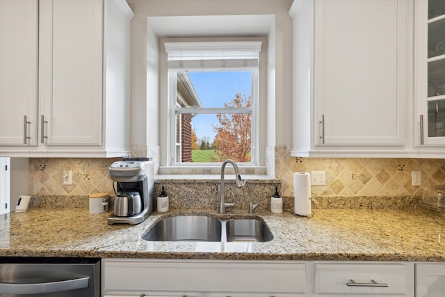 kitchen with decorative backsplash, light stone countertops, white cabinetry, and sink