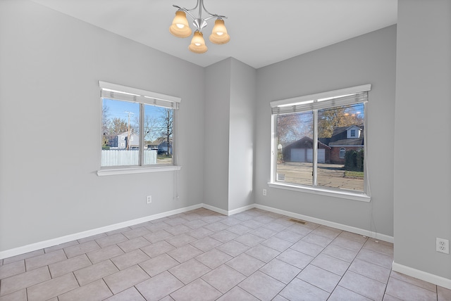 tiled spare room featuring a chandelier