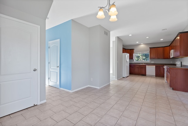 kitchen with sink, a chandelier, light tile patterned floors, pendant lighting, and white appliances