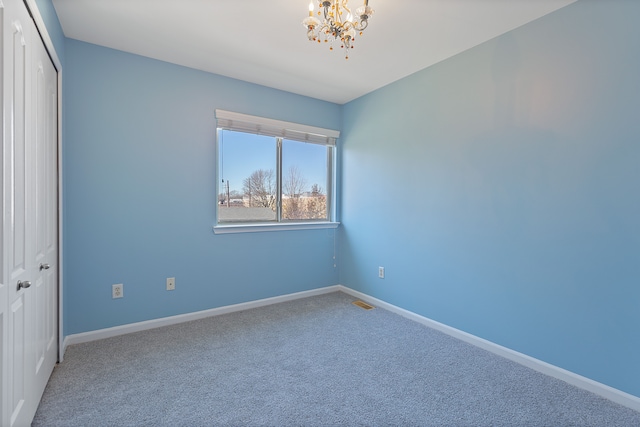 unfurnished room with an inviting chandelier and carpet flooring