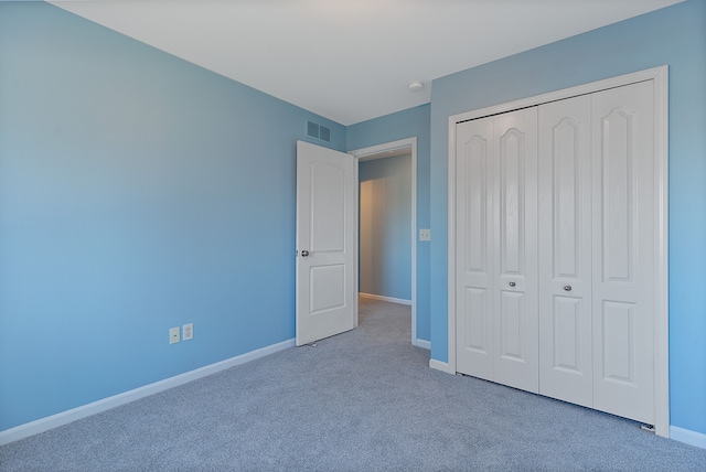 unfurnished bedroom with light colored carpet and a closet