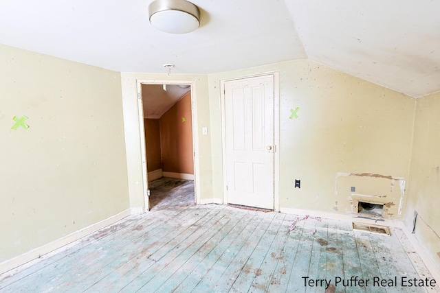 additional living space featuring light wood-type flooring and vaulted ceiling