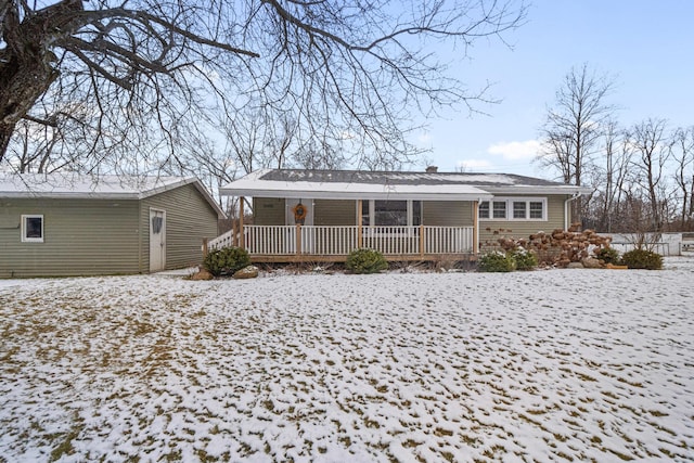 snow covered rear of property featuring covered porch