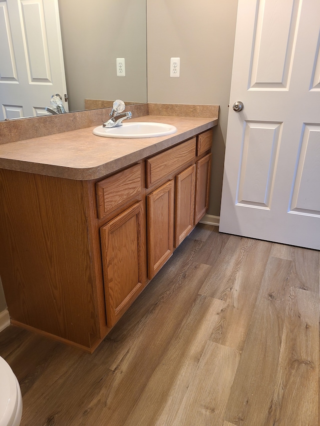 bathroom with vanity, toilet, and hardwood / wood-style floors