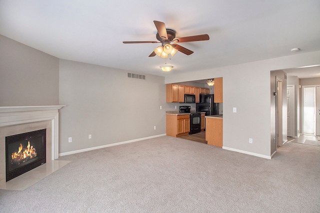 unfurnished living room with ceiling fan, light carpet, a fireplace, visible vents, and baseboards