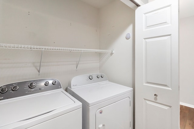 washroom with laundry area, washer and dryer, and wood finished floors