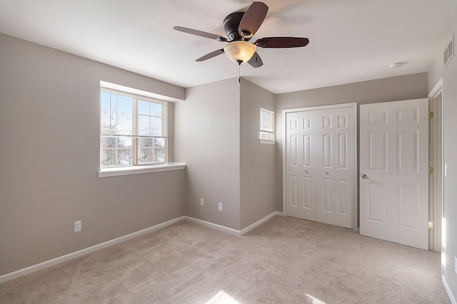 unfurnished bedroom with ceiling fan, light carpet, visible vents, baseboards, and a closet