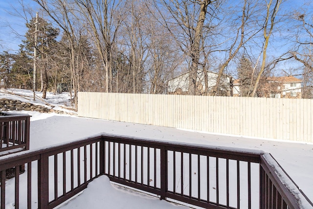 snow covered deck featuring a fenced backyard