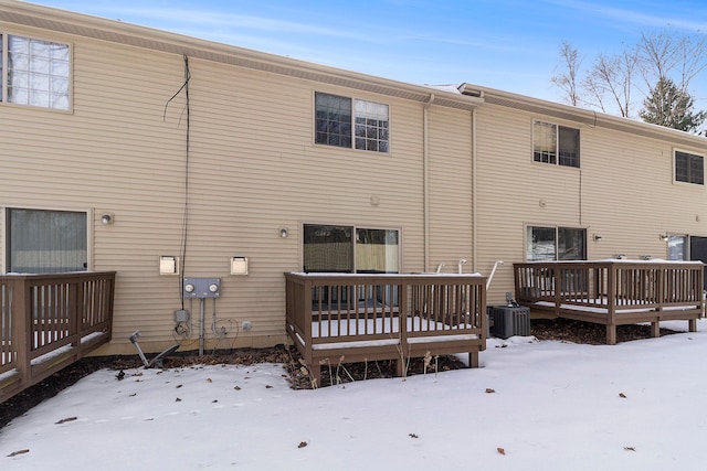 snow covered house with central AC unit and a wooden deck