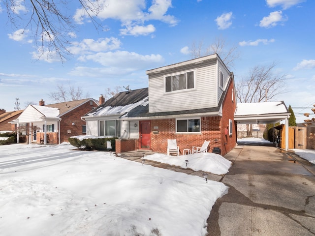 view of front of property with a carport, brick siding, driveway, and fence