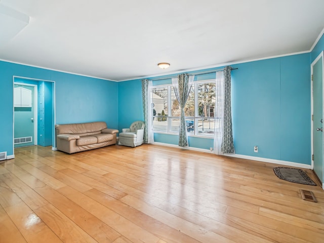 unfurnished room featuring baseboards, light wood finished floors, visible vents, and crown molding