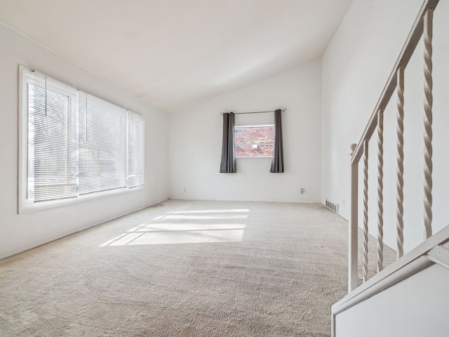 empty room featuring a wealth of natural light, carpet, visible vents, and lofted ceiling