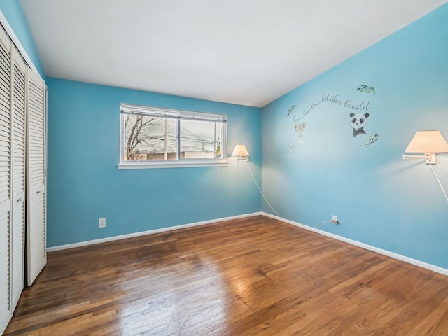 unfurnished bedroom featuring dark wood-type flooring, a closet, and baseboards