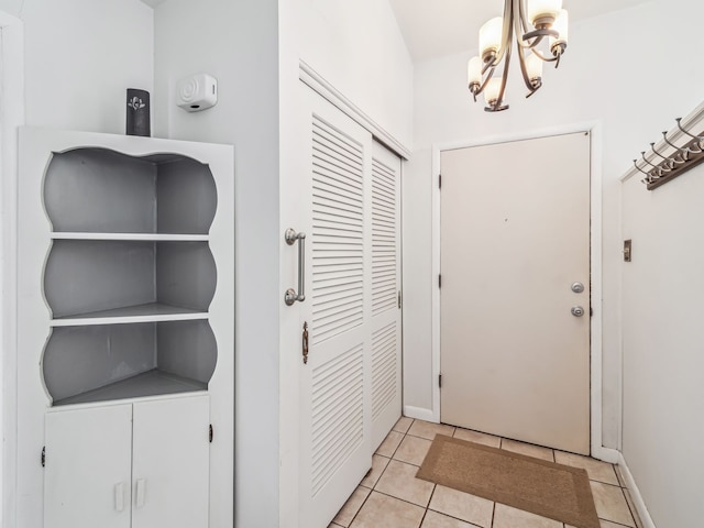 foyer featuring light tile patterned floors, baseboards, and a notable chandelier