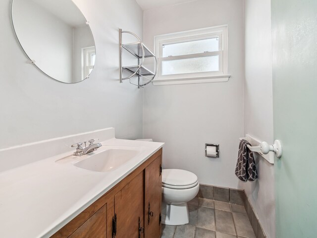 bathroom with tile patterned flooring, baseboards, vanity, and toilet