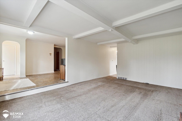 carpeted empty room with beamed ceiling