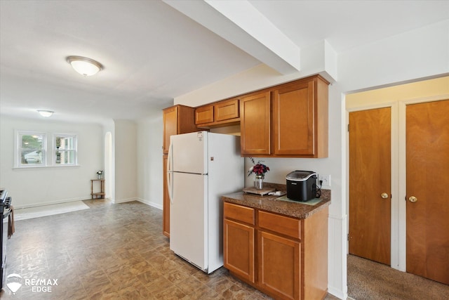 kitchen with white fridge, dark stone countertops, stainless steel electric range oven, and beam ceiling