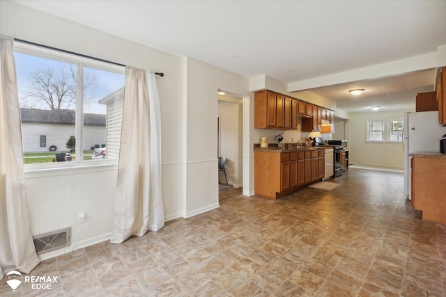 kitchen featuring white refrigerator, sink, stainless steel electric range oven, and a healthy amount of sunlight