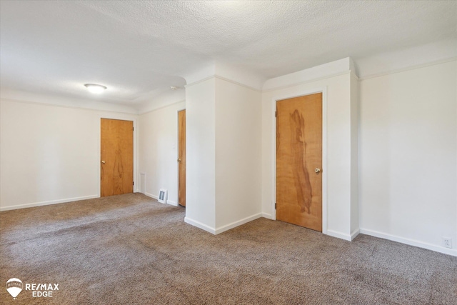 carpeted empty room featuring crown molding and a textured ceiling