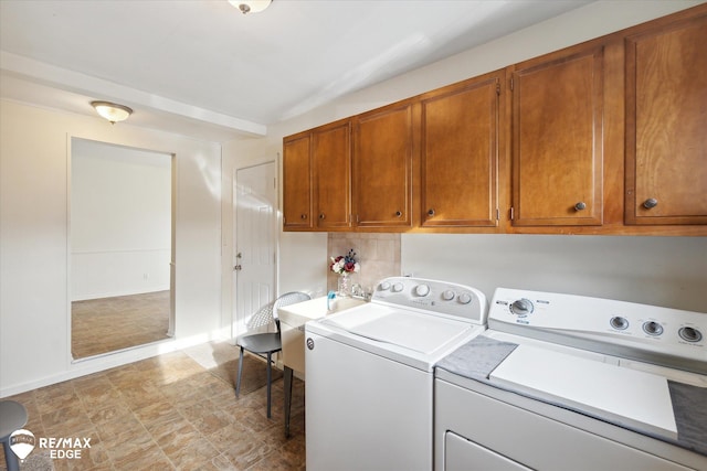 clothes washing area featuring washing machine and dryer and cabinets