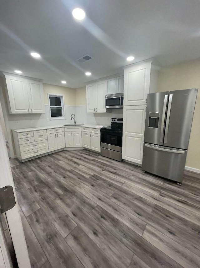 kitchen featuring appliances with stainless steel finishes, dark hardwood / wood-style flooring, white cabinetry, and sink