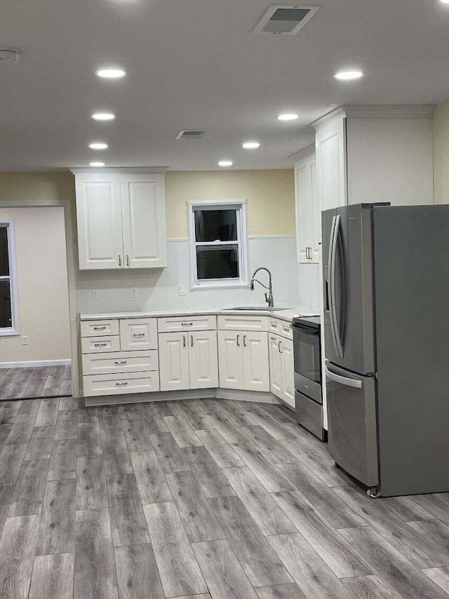 kitchen featuring white cabinetry, sink, stainless steel appliances, and light hardwood / wood-style flooring