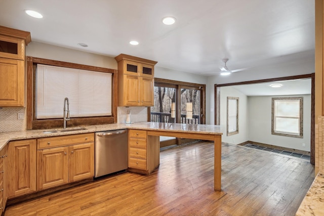 kitchen with decorative backsplash, light stone counters, stainless steel dishwasher, ceiling fan, and sink