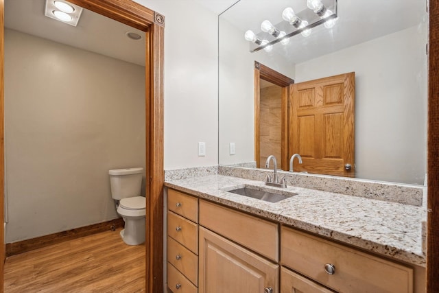 bathroom featuring wood-type flooring, vanity, and toilet