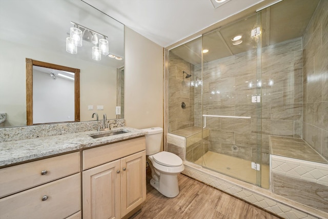 bathroom with toilet, hardwood / wood-style floors, vanity, and walk in shower