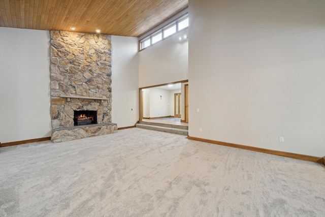 unfurnished living room featuring carpet floors, a fireplace, a towering ceiling, and wood ceiling