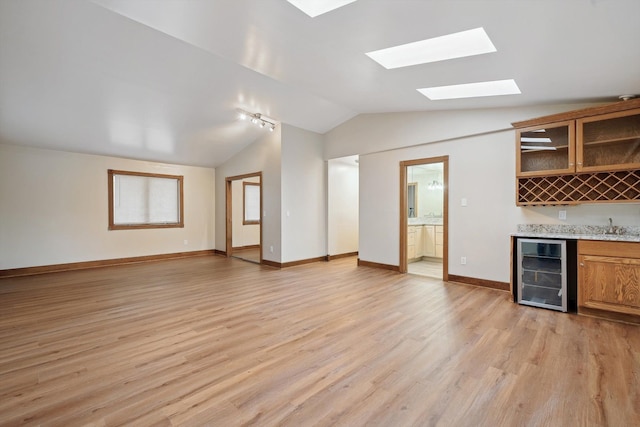 kitchen featuring vaulted ceiling, light hardwood / wood-style flooring, wine cooler, and sink