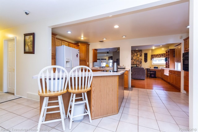 8268 Doncaster Dr, Sterling Heights, MI 48312 - kitchen with white fridge with ice dispenser, a peninsula, light countertops, brown cabinetry, and recessed lighting