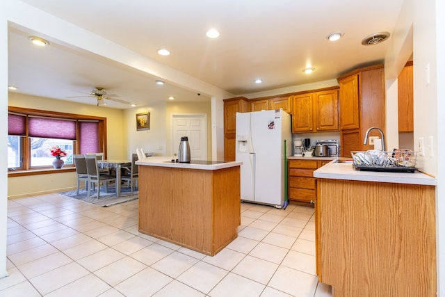 kitchen featuring light tile patterned flooring, sink, ceiling fan, white fridge with ice dispenser, and a kitchen island