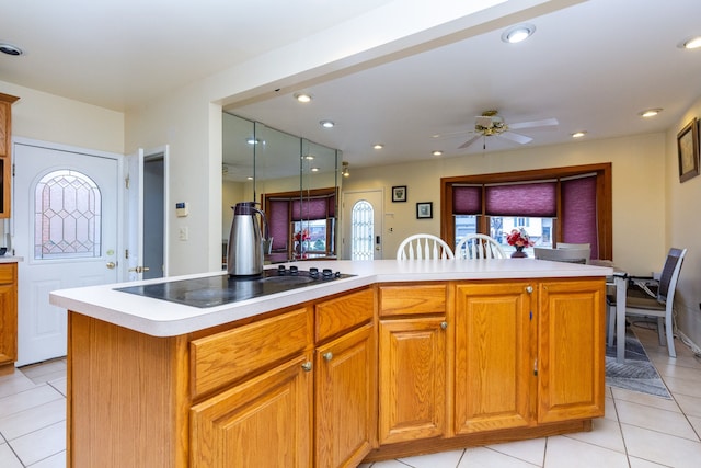 kitchen with stovetop, a center island, light tile patterned floors, and ceiling fan