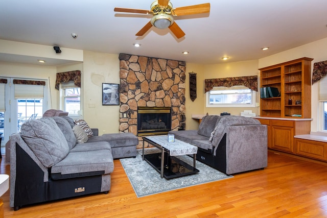 living room featuring ceiling fan, light hardwood / wood-style floors, and a fireplace