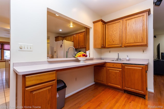 8268 Doncaster Dr, Sterling Heights, MI 48312 - kitchen with white fridge with ice dispenser, brown cabinets, light wood-style flooring, light countertops, and a peninsula