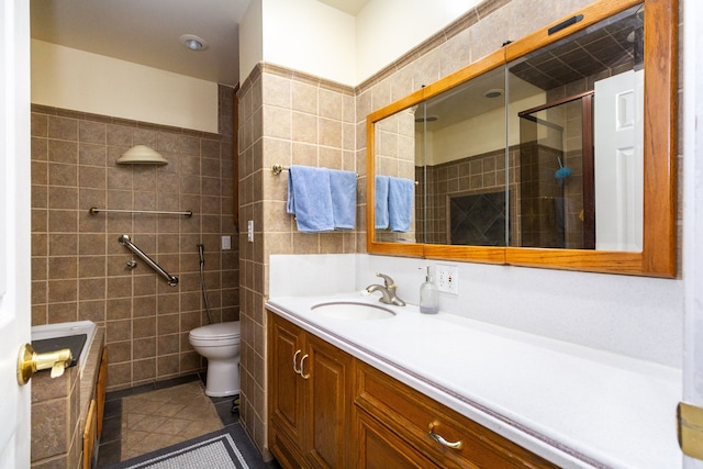 bathroom with tile patterned floors, vanity, tiled shower, tile walls, and toilet