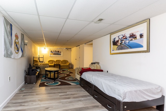 bedroom featuring a paneled ceiling and light hardwood / wood-style floors