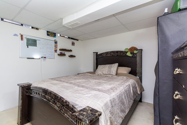 carpeted bedroom featuring a drop ceiling