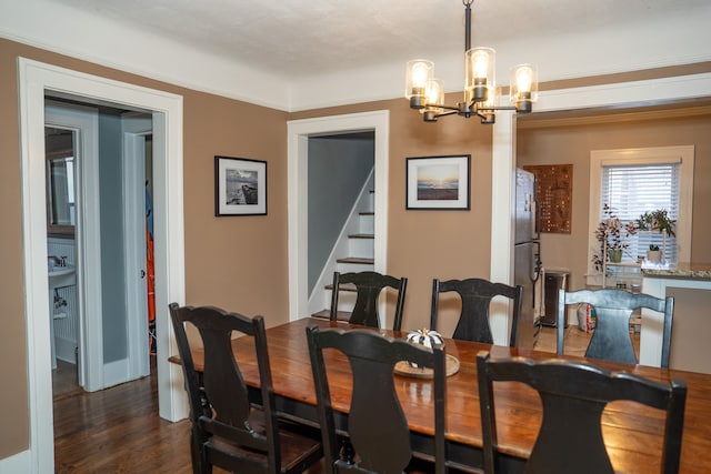 dining space featuring ornamental molding, dark wood-type flooring, and a notable chandelier