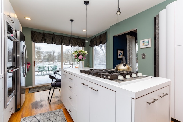 kitchen featuring appliances with stainless steel finishes, white cabinetry, and hanging light fixtures