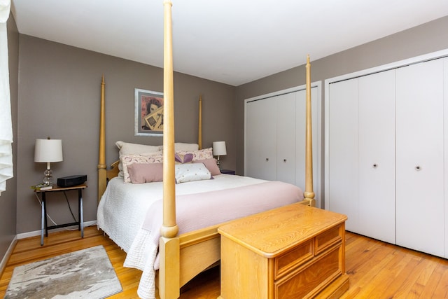 bedroom with multiple closets and light hardwood / wood-style flooring