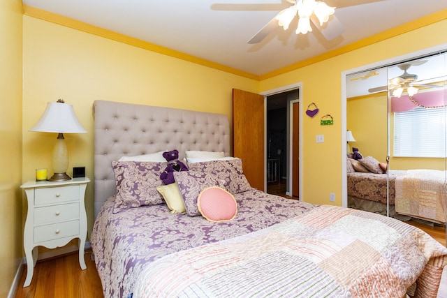 bedroom with ceiling fan, wood-type flooring, ornamental molding, and a closet