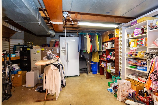 basement featuring white refrigerator with ice dispenser