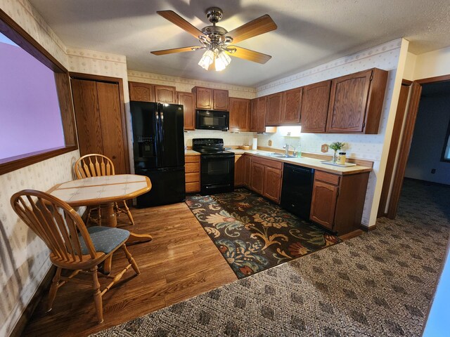 kitchen with a textured ceiling, ceiling fan, sink, black appliances, and dark hardwood / wood-style floors