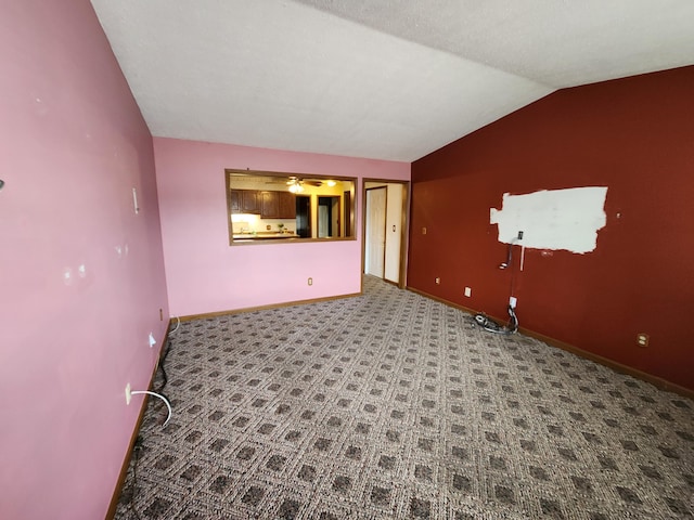 carpeted spare room with vaulted ceiling