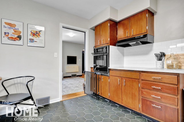 kitchen with black oven, stovetop, dark tile patterned floors, and tasteful backsplash