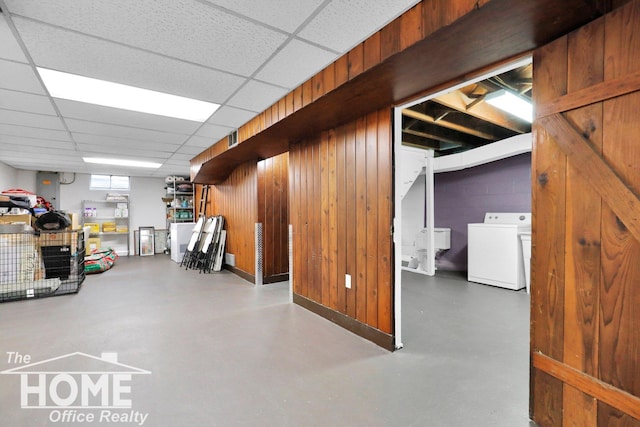 basement with washer / clothes dryer, a drop ceiling, and wood walls