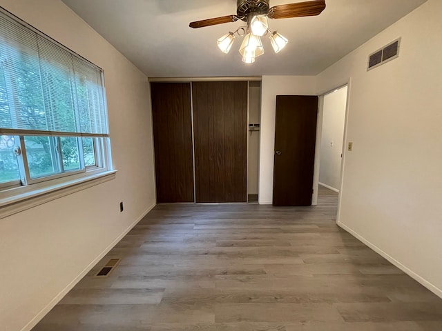 unfurnished bedroom featuring ceiling fan, a closet, and light hardwood / wood-style flooring